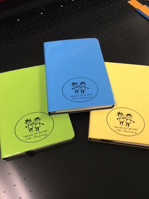 Three notebooks are sitting on a table and one of them says keep it real