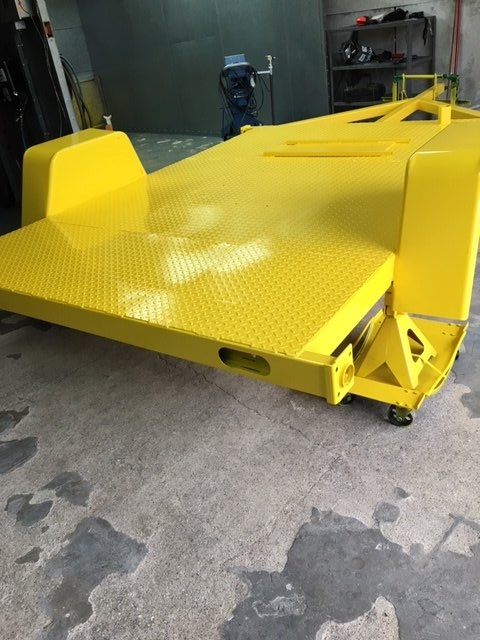 A yellow vehicle is sitting on the ground in a garage