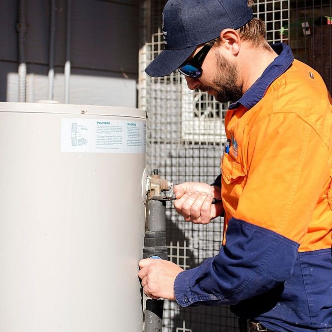 A Townsville plumber working on a water heater