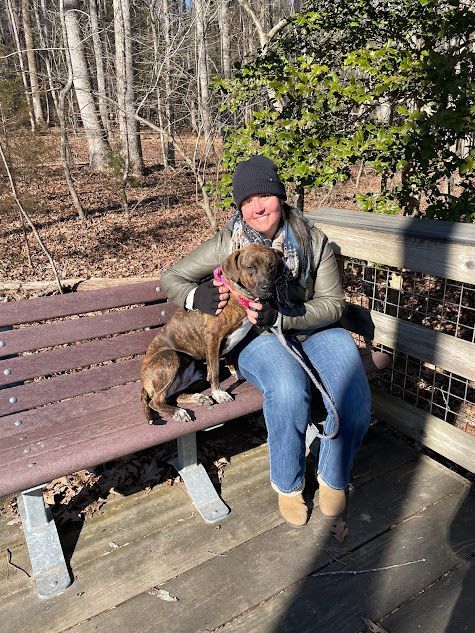 Trainer hanging out with a dog practicing Place on a trail hike in Wendell, NC, reinforcing obedience and stability in an outdoor environment. Dog training in Wendell focuses on building focus and good behavior in natural settings, helping dogs stay calm and responsive on hikes.