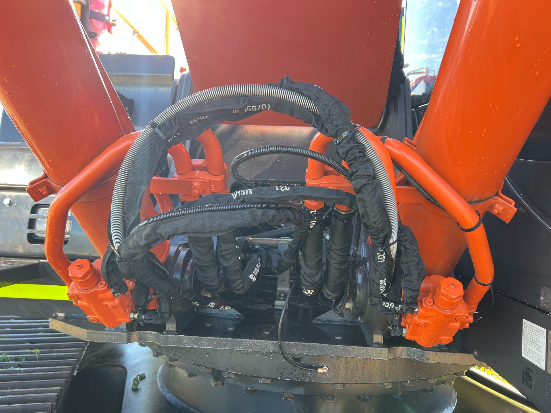 Close-up of orange hydraulic machinery with black hoses and connections.