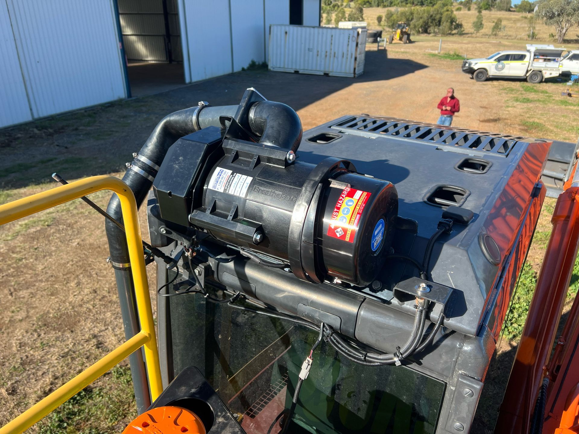 Red excavator with a glass cabin, in a field on a sunny day.