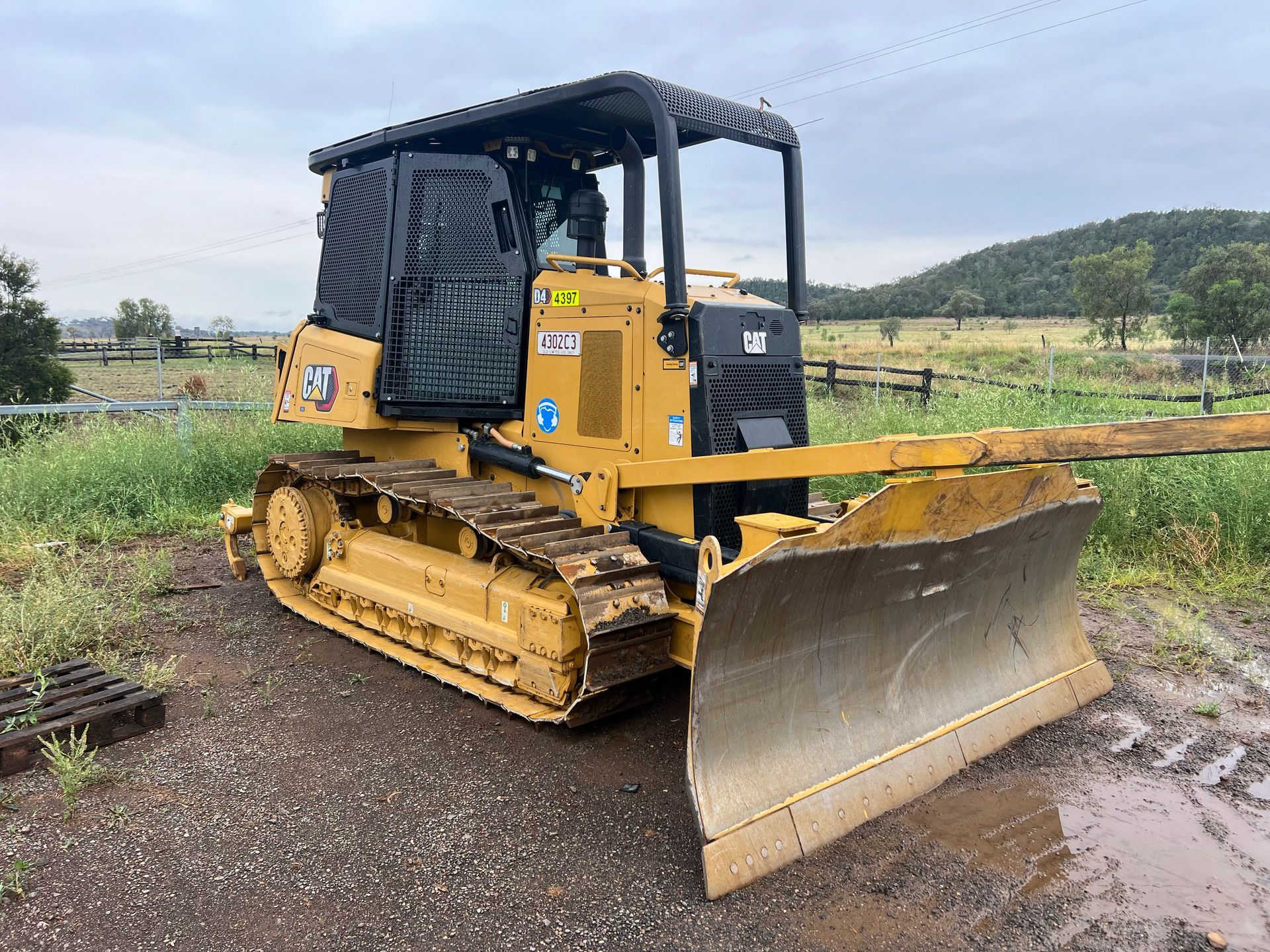 Yellow bulldozer with a blade on a muddy construction site.