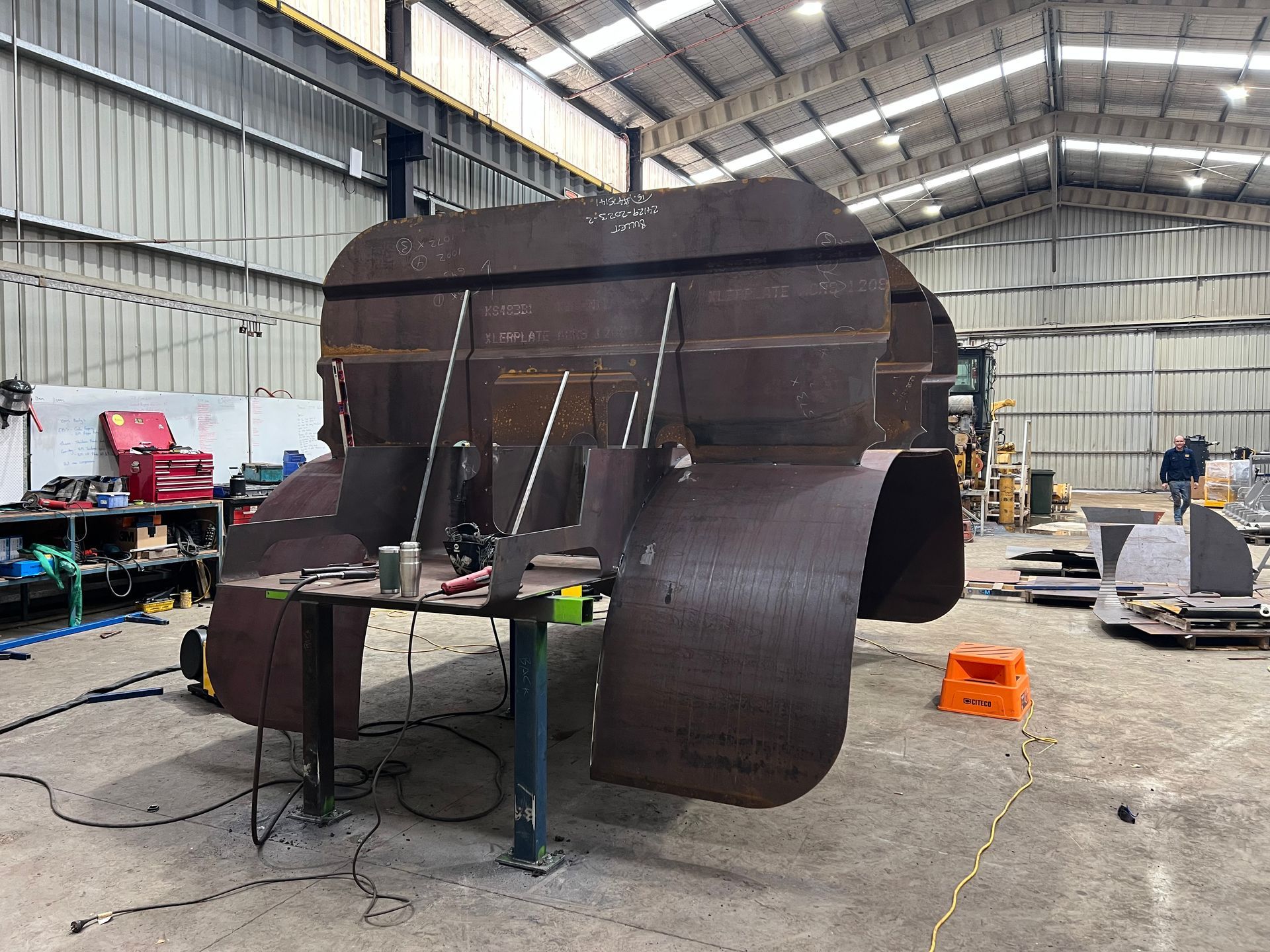 Metal structure under construction in a warehouse. Rust-colored metal sheets welded together.