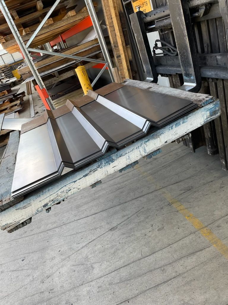 Four metal sheets on a forklift platform in a warehouse.