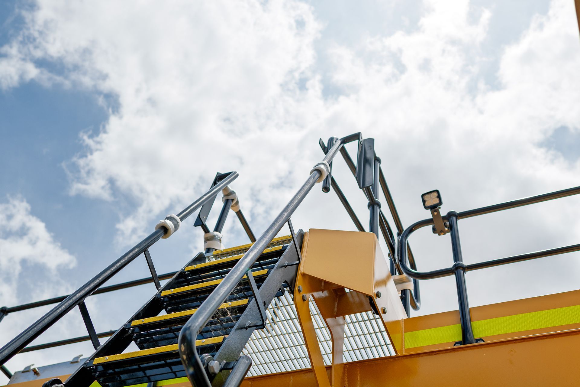 Yellow mining truck with black ladder and tire.