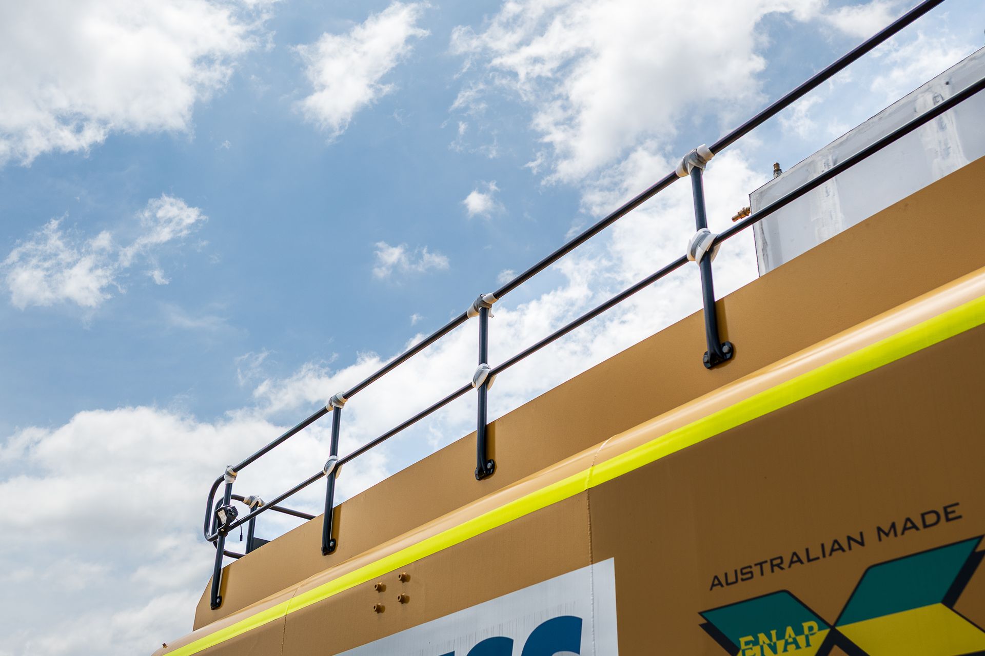 Construction worker in yellow shirt and hard hat waves from heavy machinery cab.