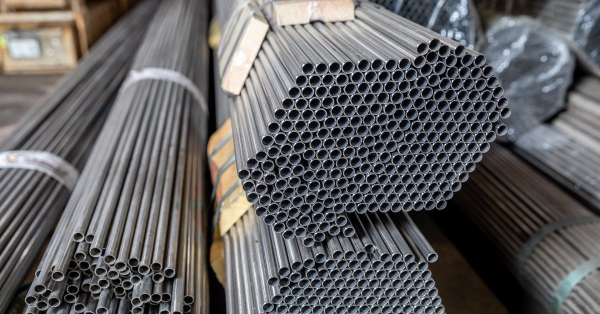 Several bundles of long, thin steel pipes strapped together and piled up on top of each other.