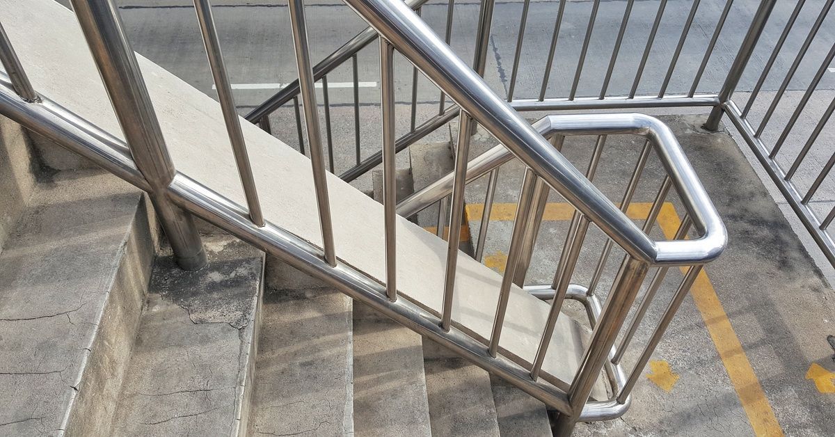 Outdoor stairs with concrete steps and a silver railing. There's yellow paint visible on the middle landing.