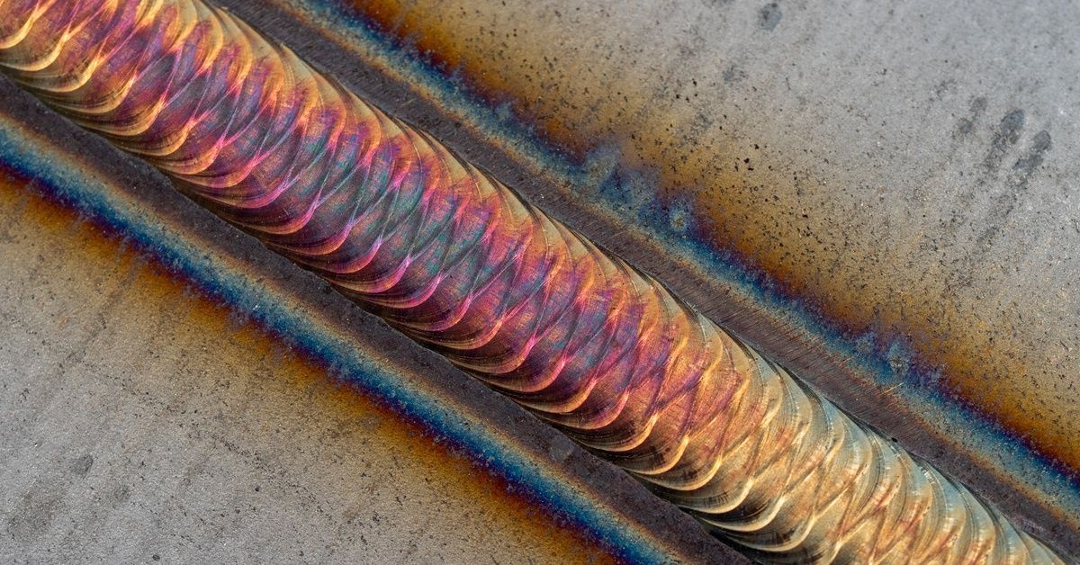 A closeup of a poor bead weld showing bright surface discoloration and visible overheating around th