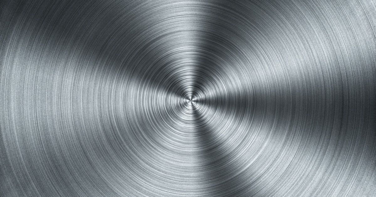 Close-up of a brushed metal surface with a circular grain pattern, creating textured radial lines in the steel.