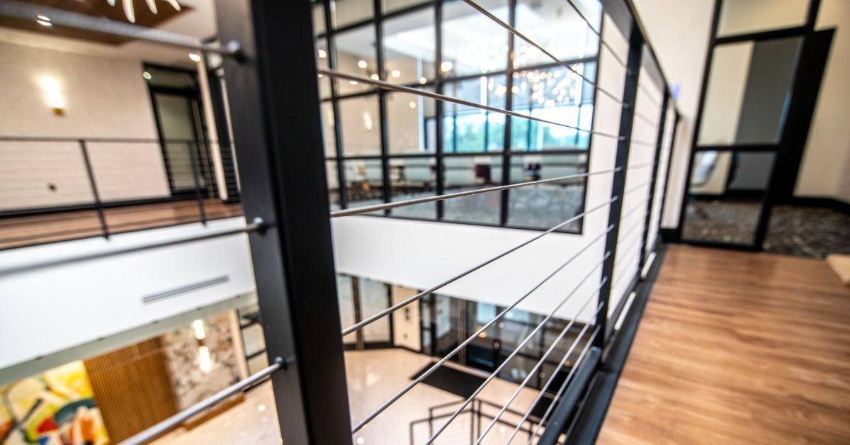 Modern interior with black cable railing along an upstairs walkway overlooking an open-concept space.