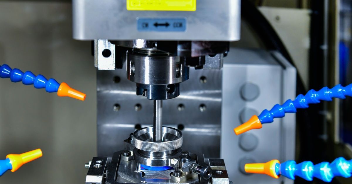 A precision machine drills a metal component, with coolant nozzles positioned around the tool in an industrial setting.