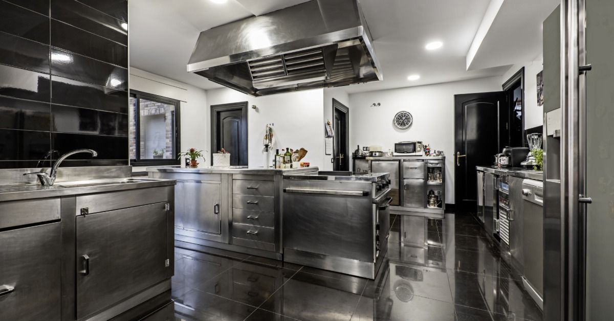 Modern residential kitchen with stainless steel cabinets, a large range hood, and a central island.