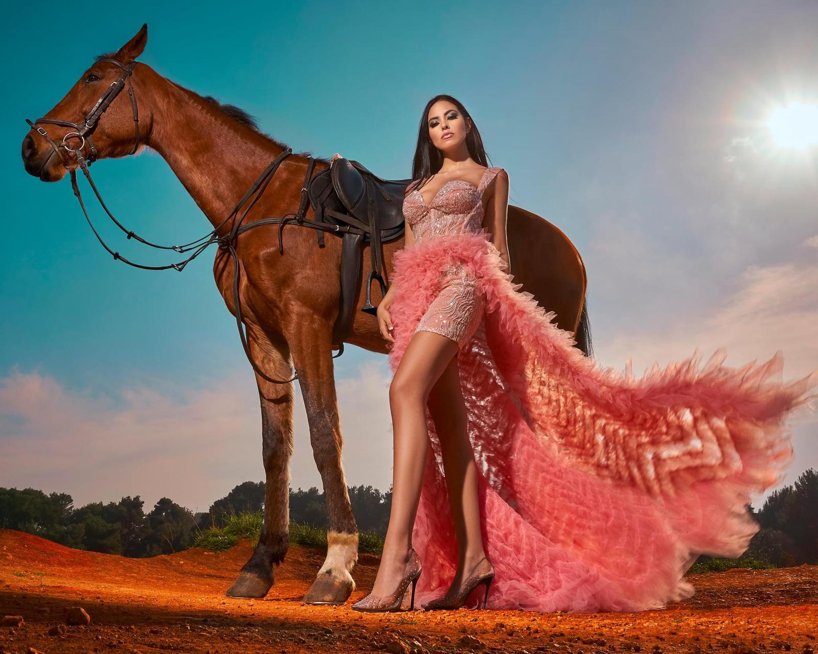 Ragazza con abito a piume arancione e cavallo accanto