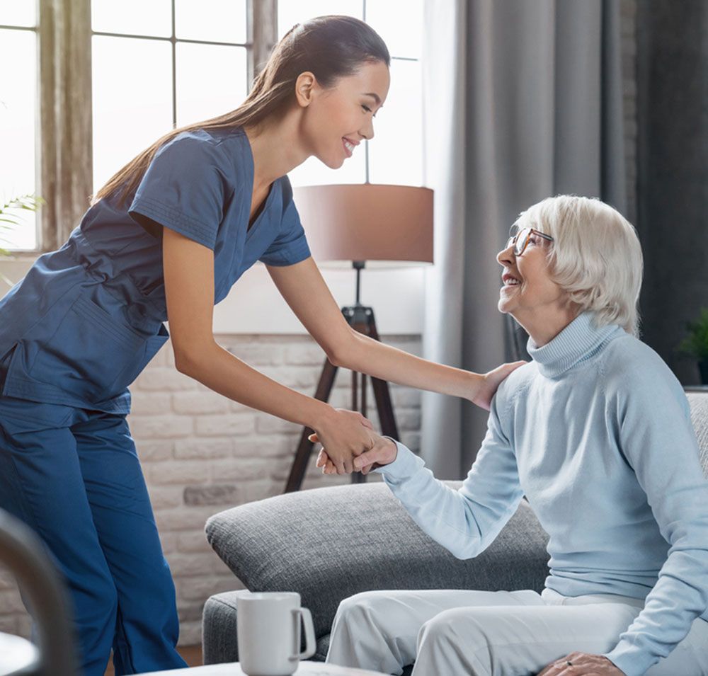 Twinlake nurse is talking to an elderly woman who is sitting on a couch.