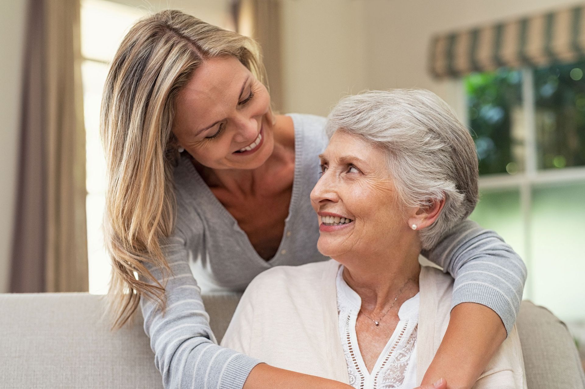 Twinlake woman is hugging an older woman on a couch.
