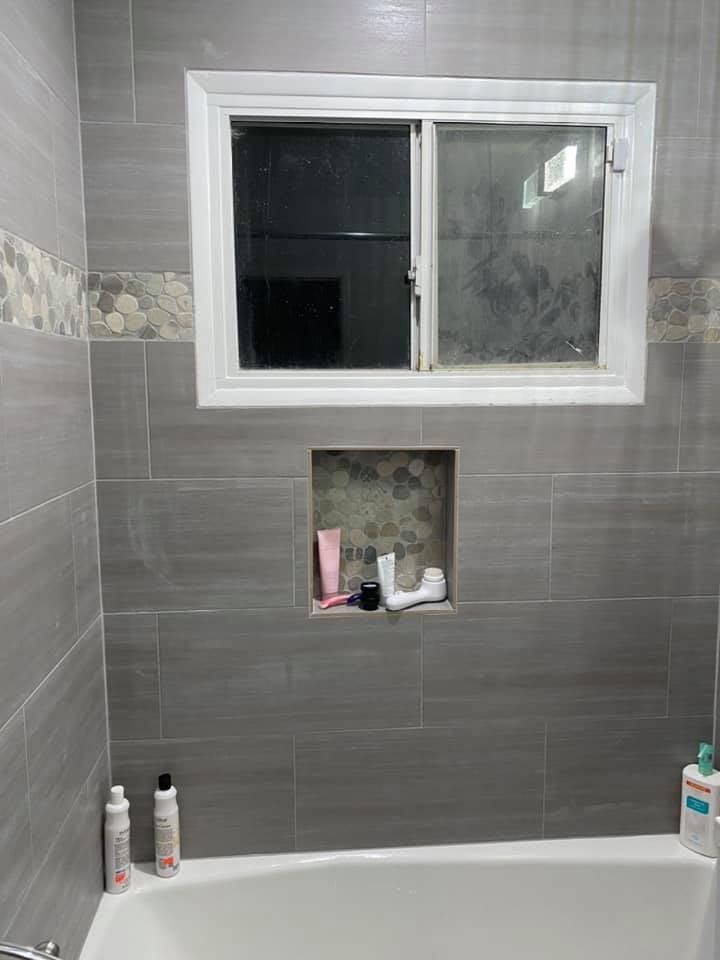 A bathroom with a bathtub and a window.