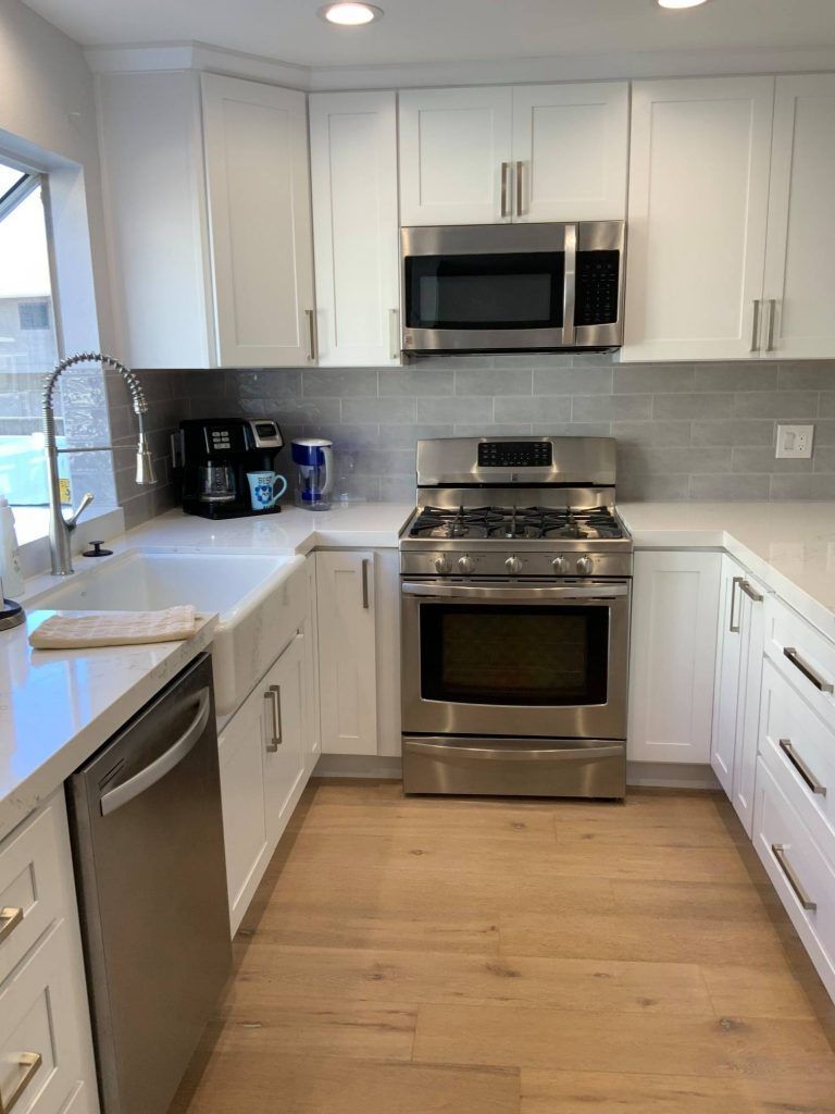 A kitchen with stainless steel appliances and white cabinets.