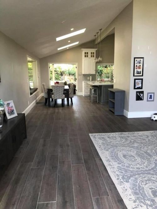 A living room with hardwood floors leading to a dining room and kitchen.