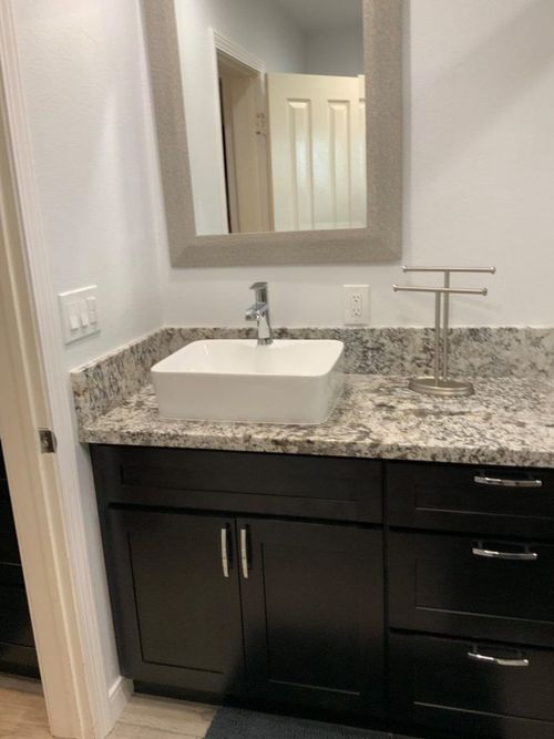 A bathroom with a sink , mirror and cabinets.