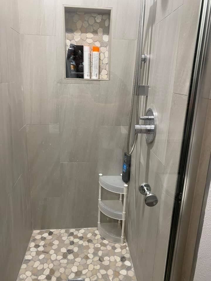 A shower stall with a glass door and a shelf.