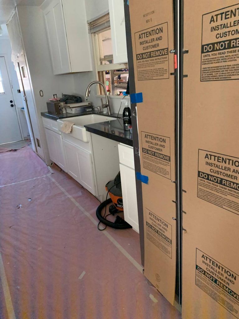 A kitchen with a refrigerator and a vacuum cleaner in it.