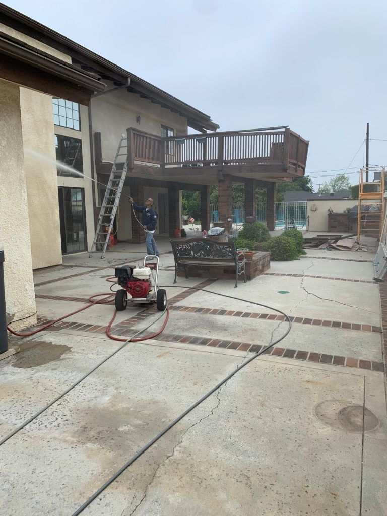 A man is standing in front of a house with a ladder.