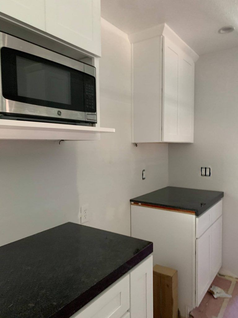 A kitchen with a microwave and a black counter top