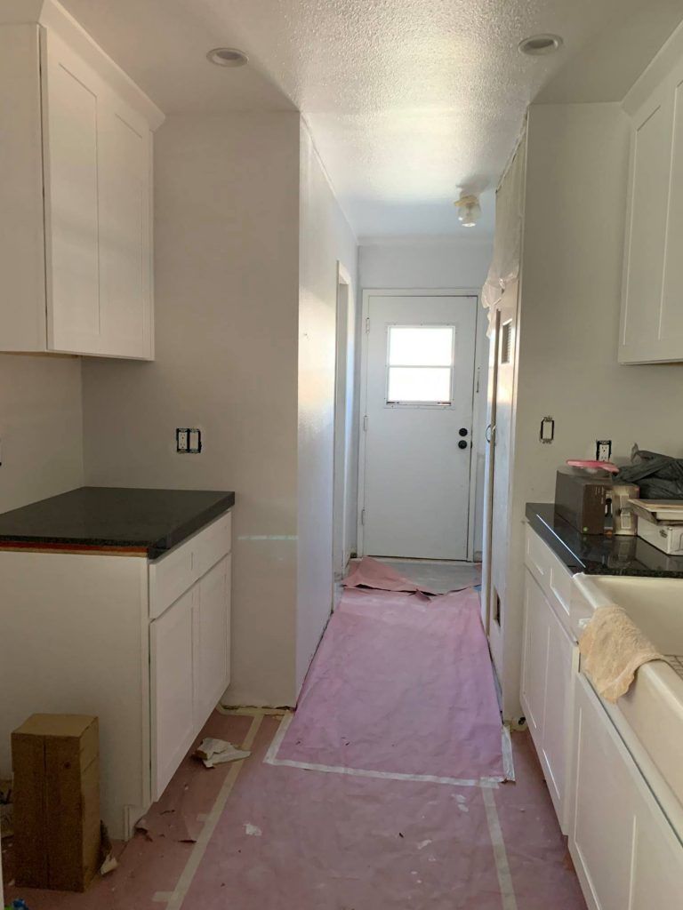 A kitchen with white cabinets and a black counter top