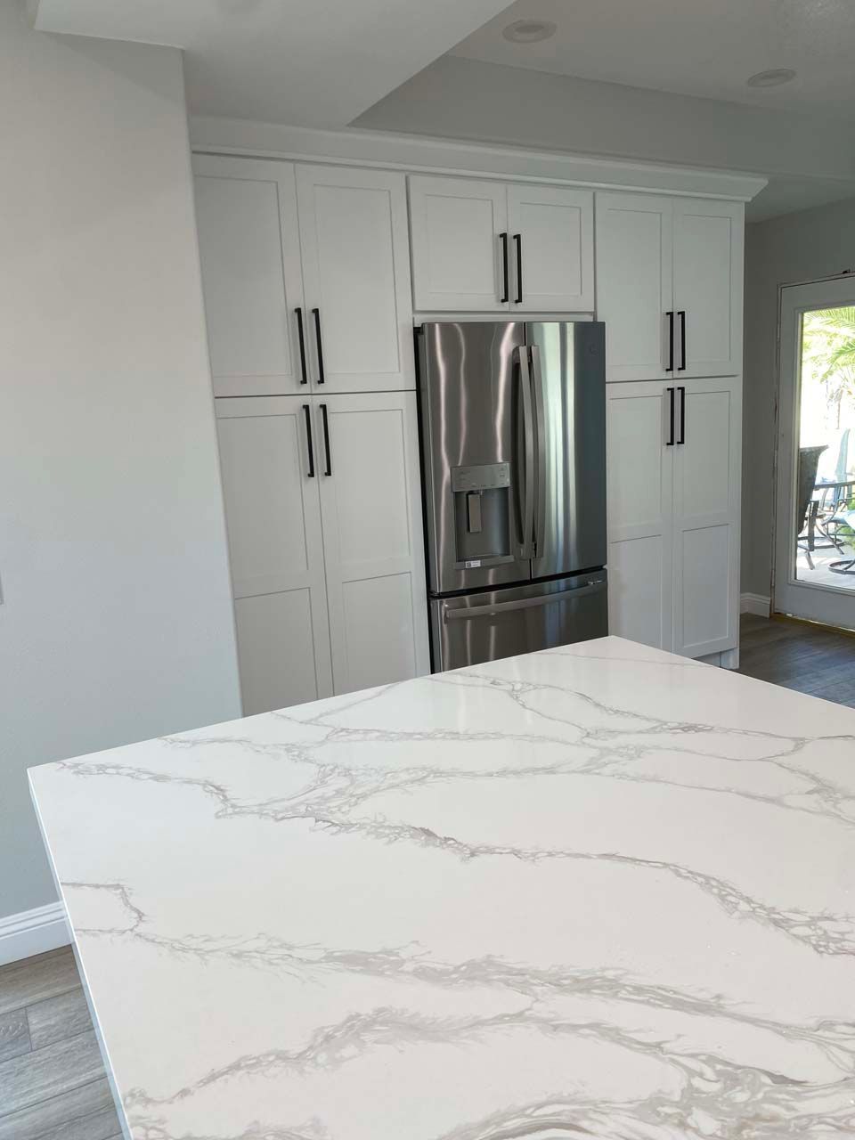 A kitchen with white cabinets and a stainless steel refrigerator.