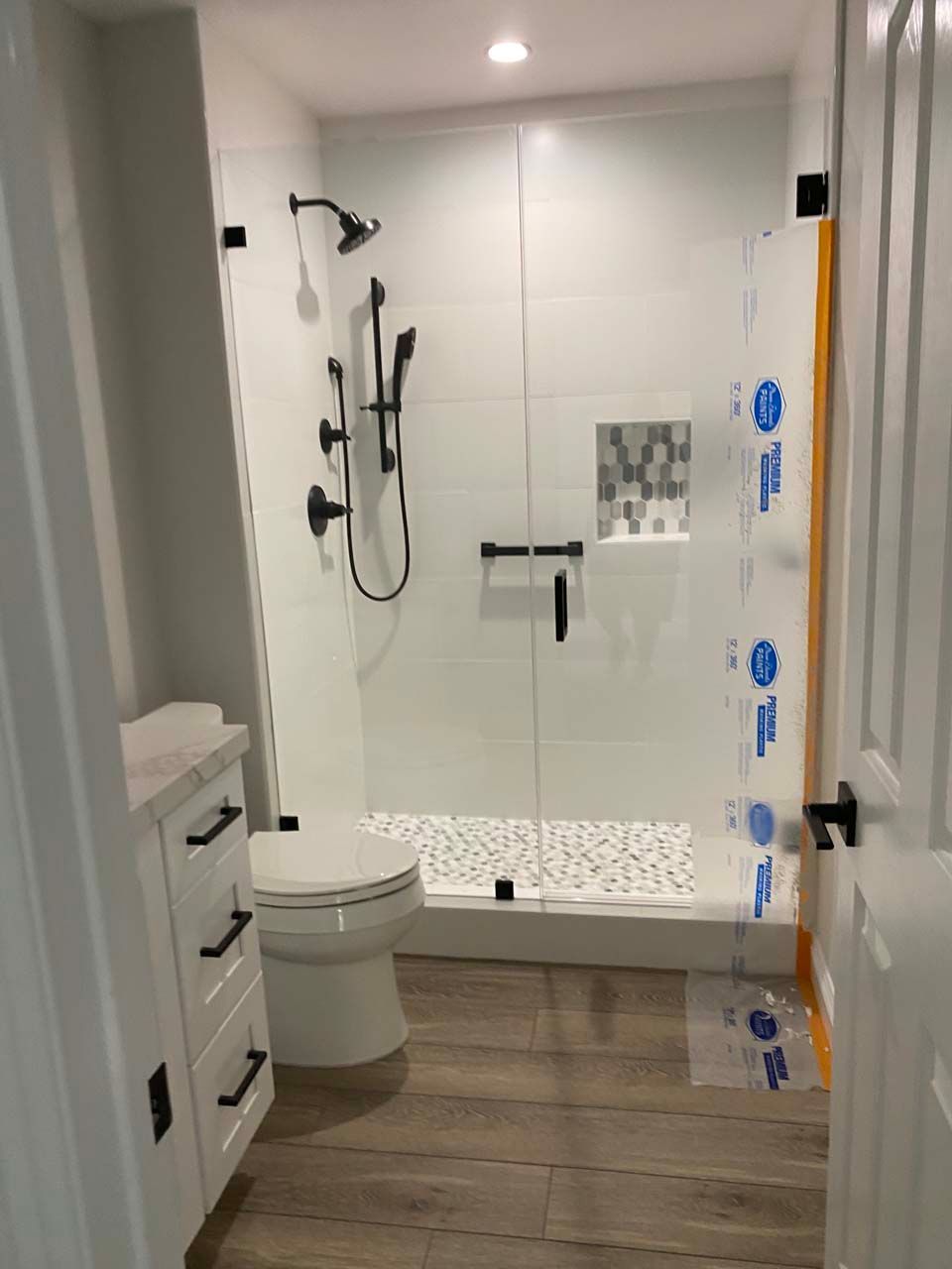A bathroom with a toilet , shower , and vanity.