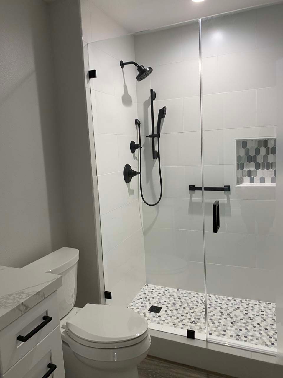 A bathroom with a toilet , sink and shower.