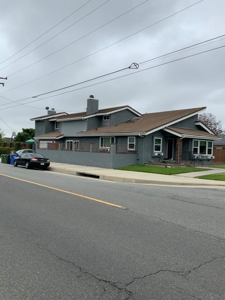 A car is parked on the side of the road in front of a house.