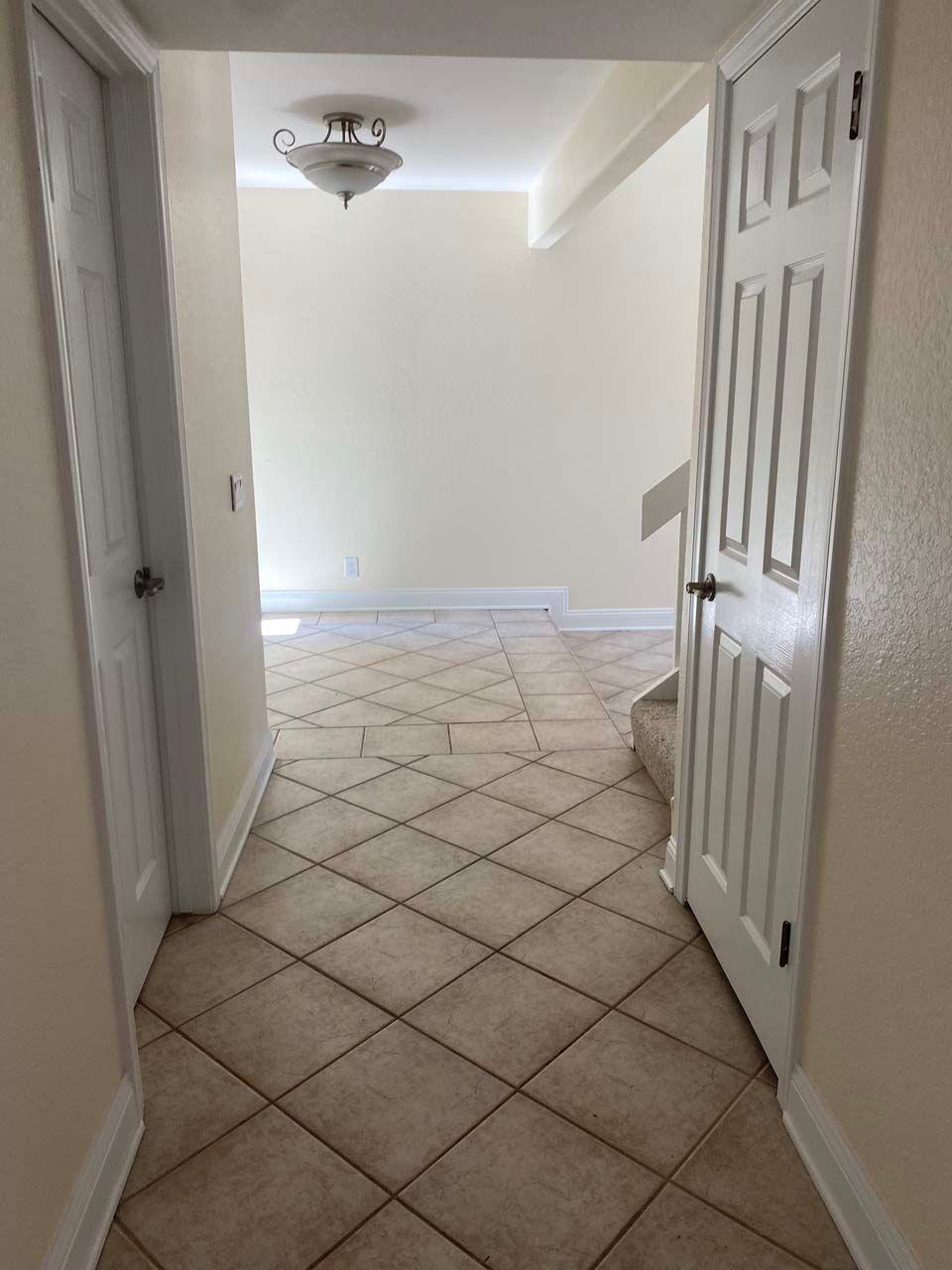 A hallway with a tiled floor and stairs in a house.