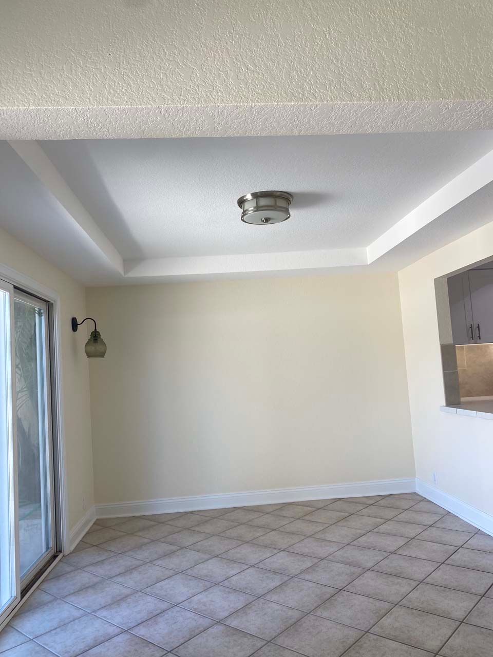 An empty living room with a sliding glass door and a light on the ceiling.