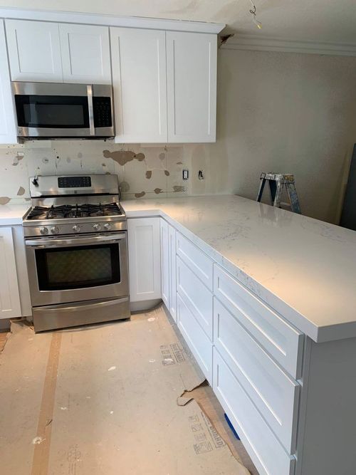 A kitchen with white cabinets , stainless steel appliances , and a large island.