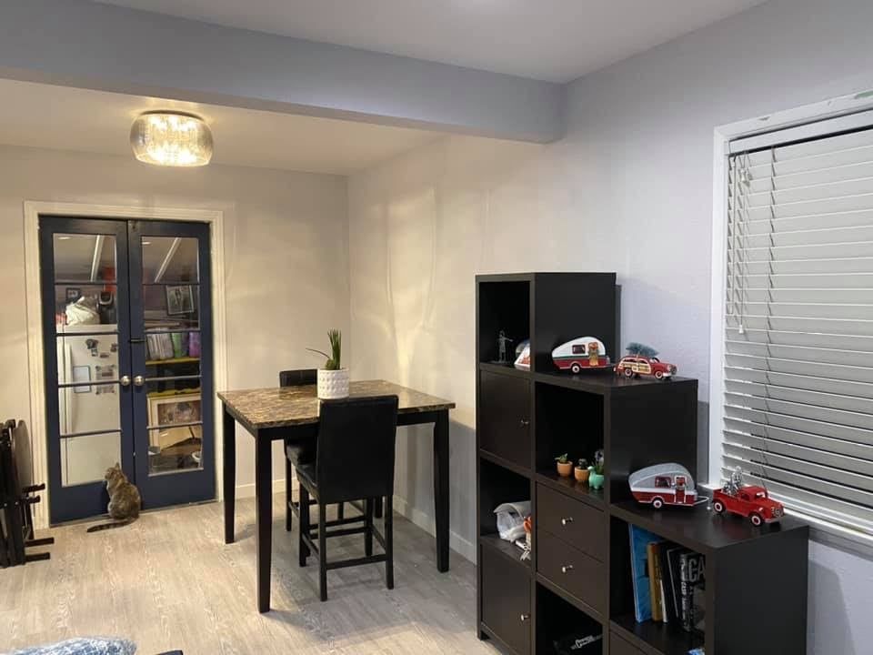 A living room with a table , chairs , shelves and blinds.