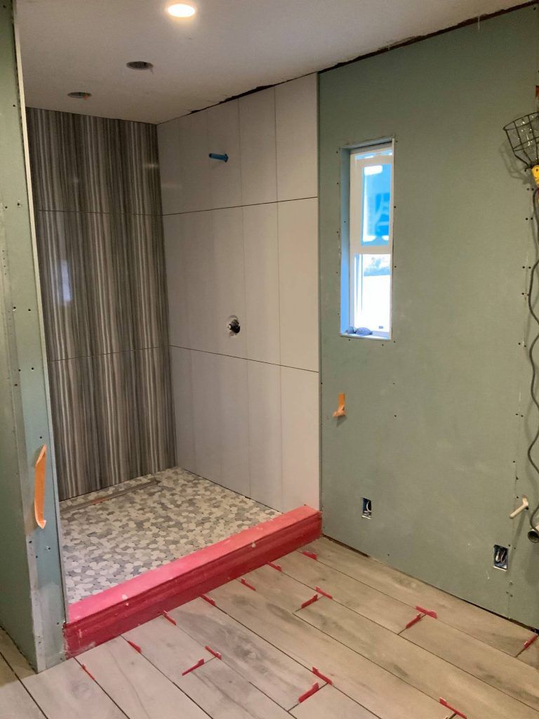 A bathroom under construction with a walk in shower and a window.