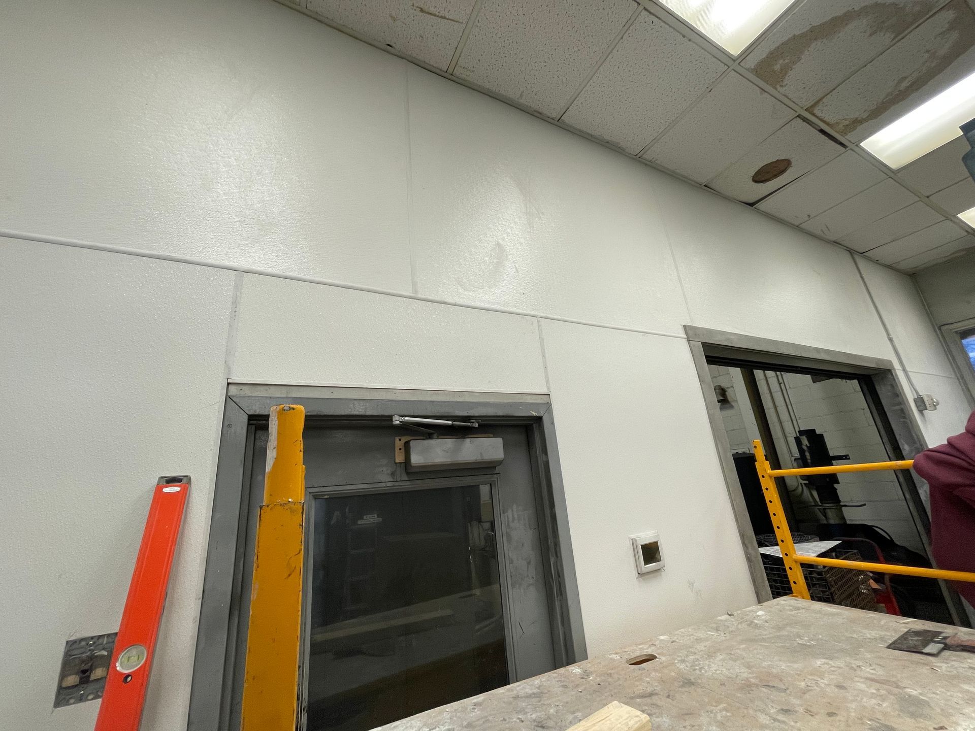 Industrial room with open windows, a ladder, and a worker near a large tank or platform