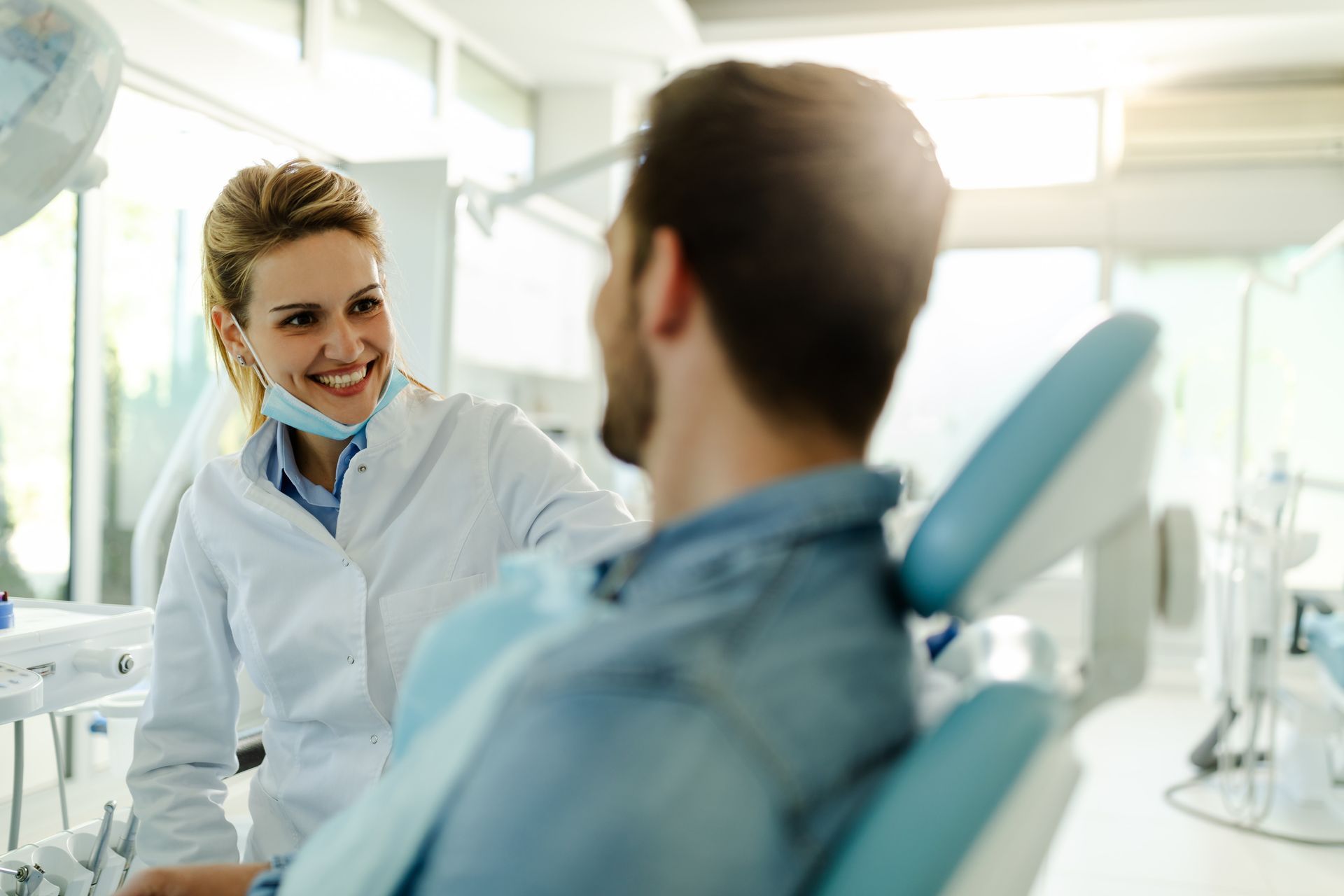 A female dentist is talking with a happy male patient at a clinic. A female dentist is talking with a happy male patient at a clinic.