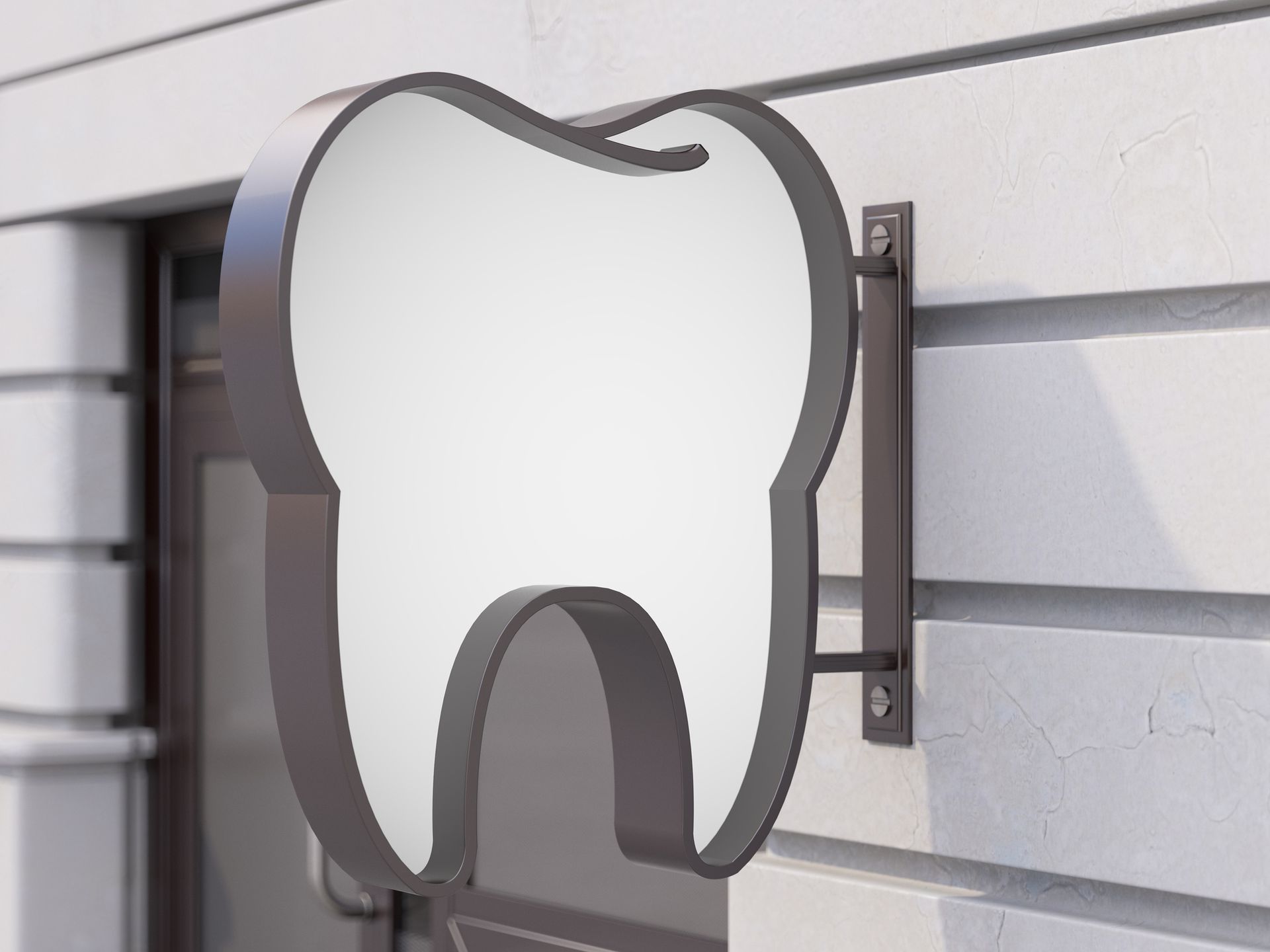 A sign in the shape of a tooth is on the side of a building.