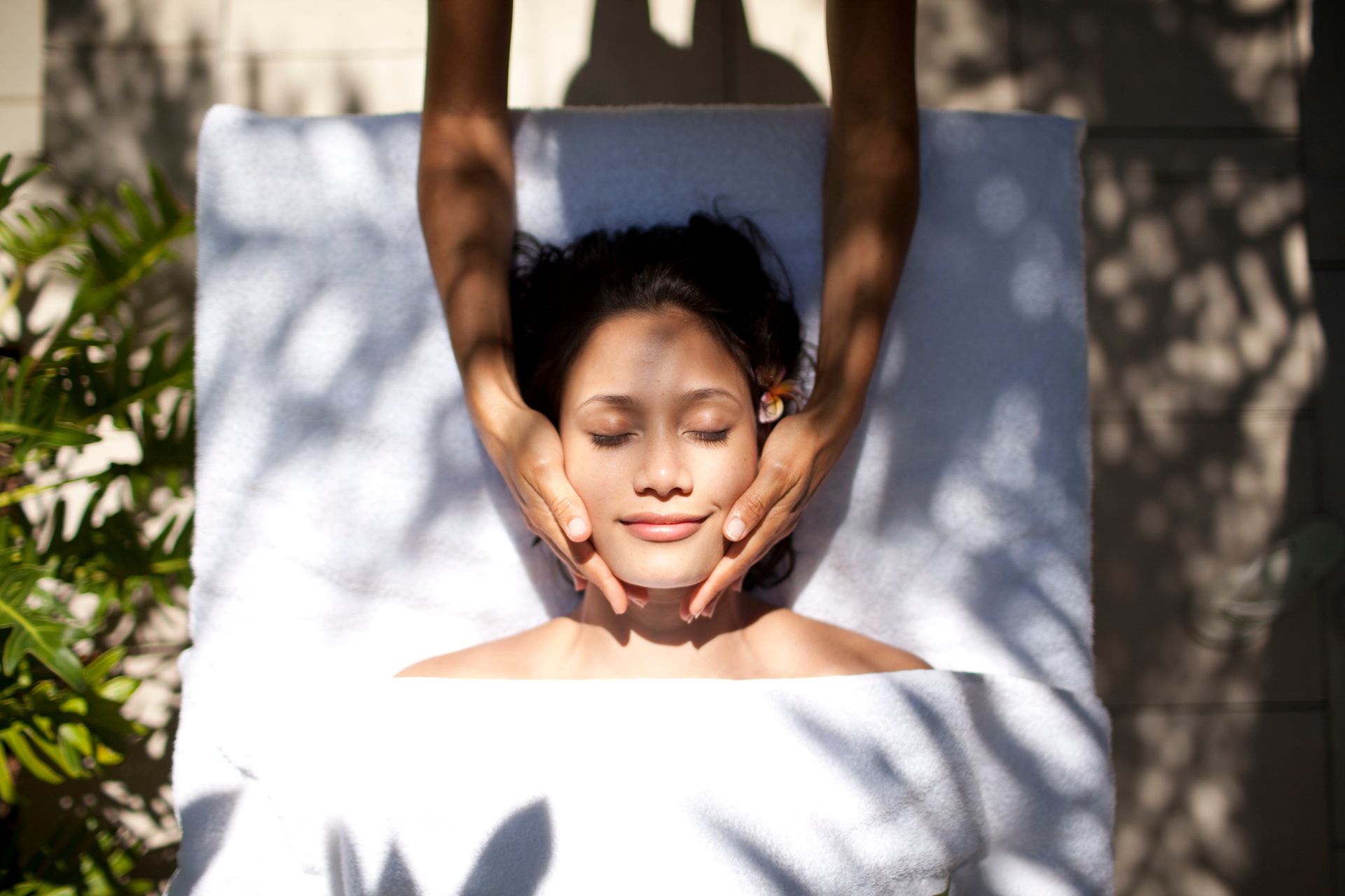 A woman is laying on a bed getting a massage on her face.