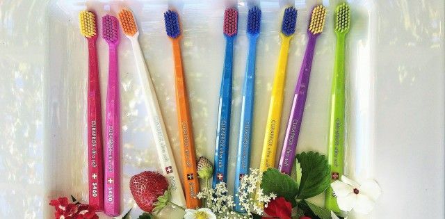 A row of colorful toothbrushes sitting on top of a white plate.