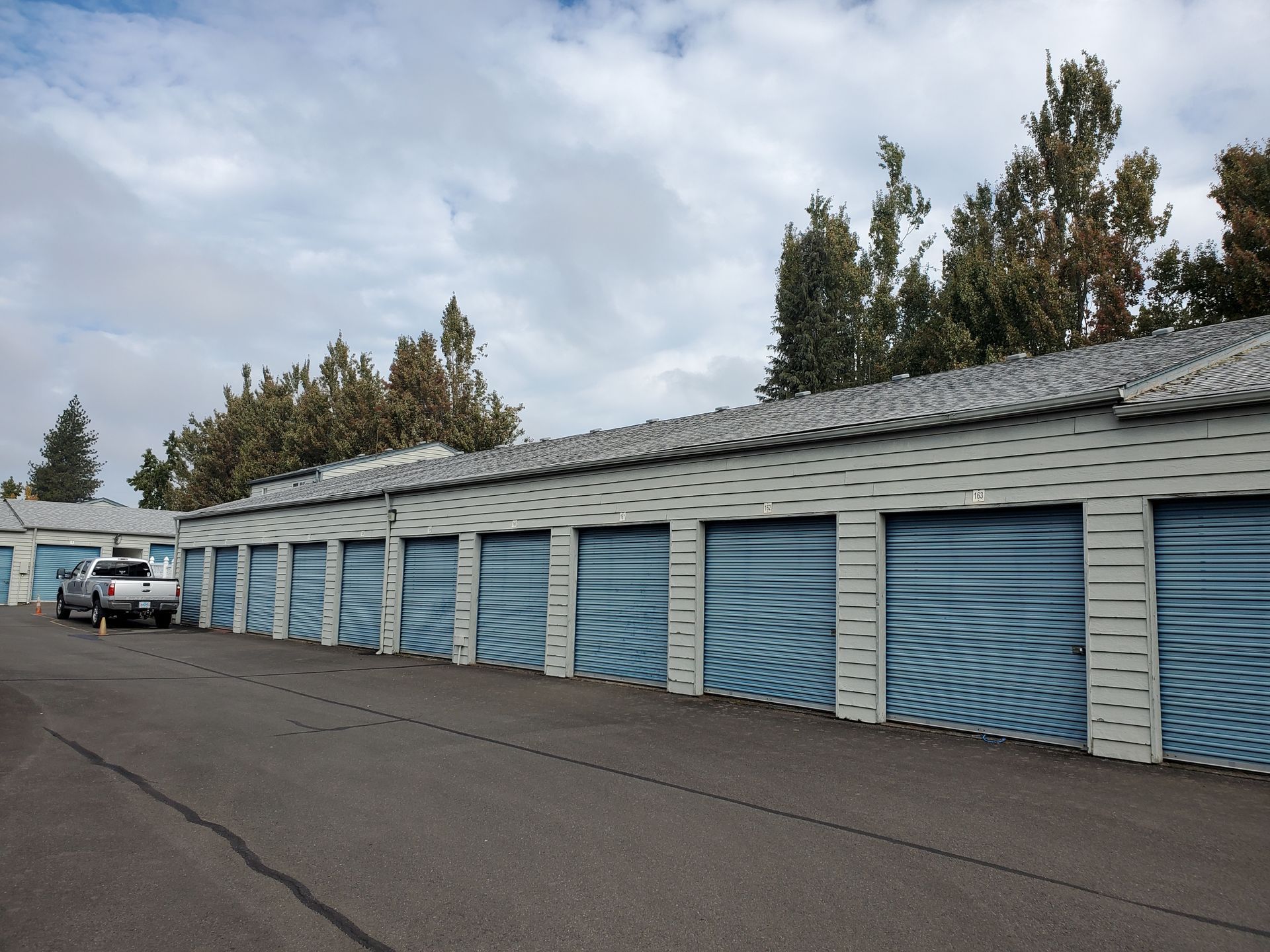 Storage unit, partially open, filled with packed boxes, furniture, and a mattress.