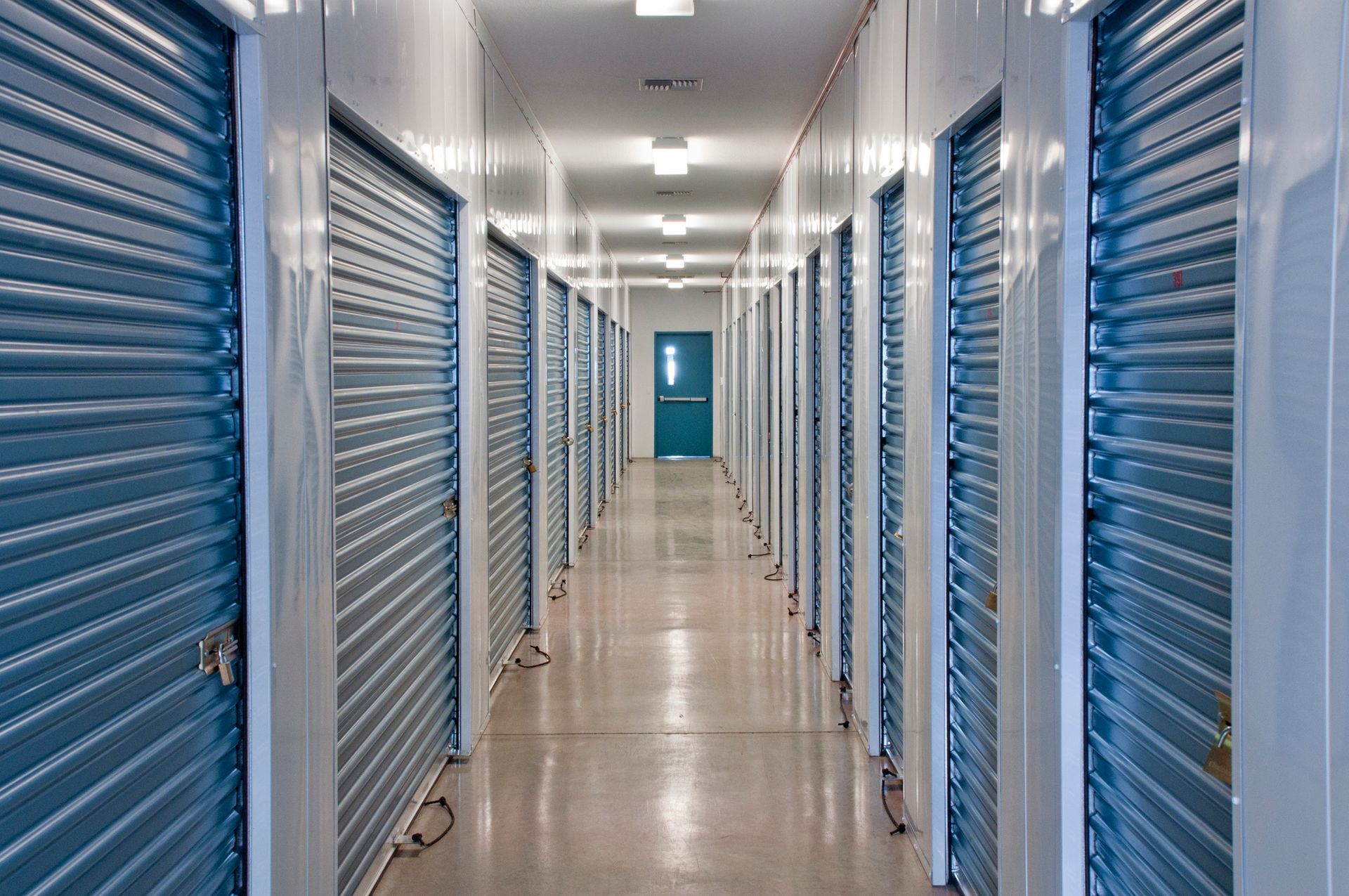 Row of red brick storage units with red rolling doors.