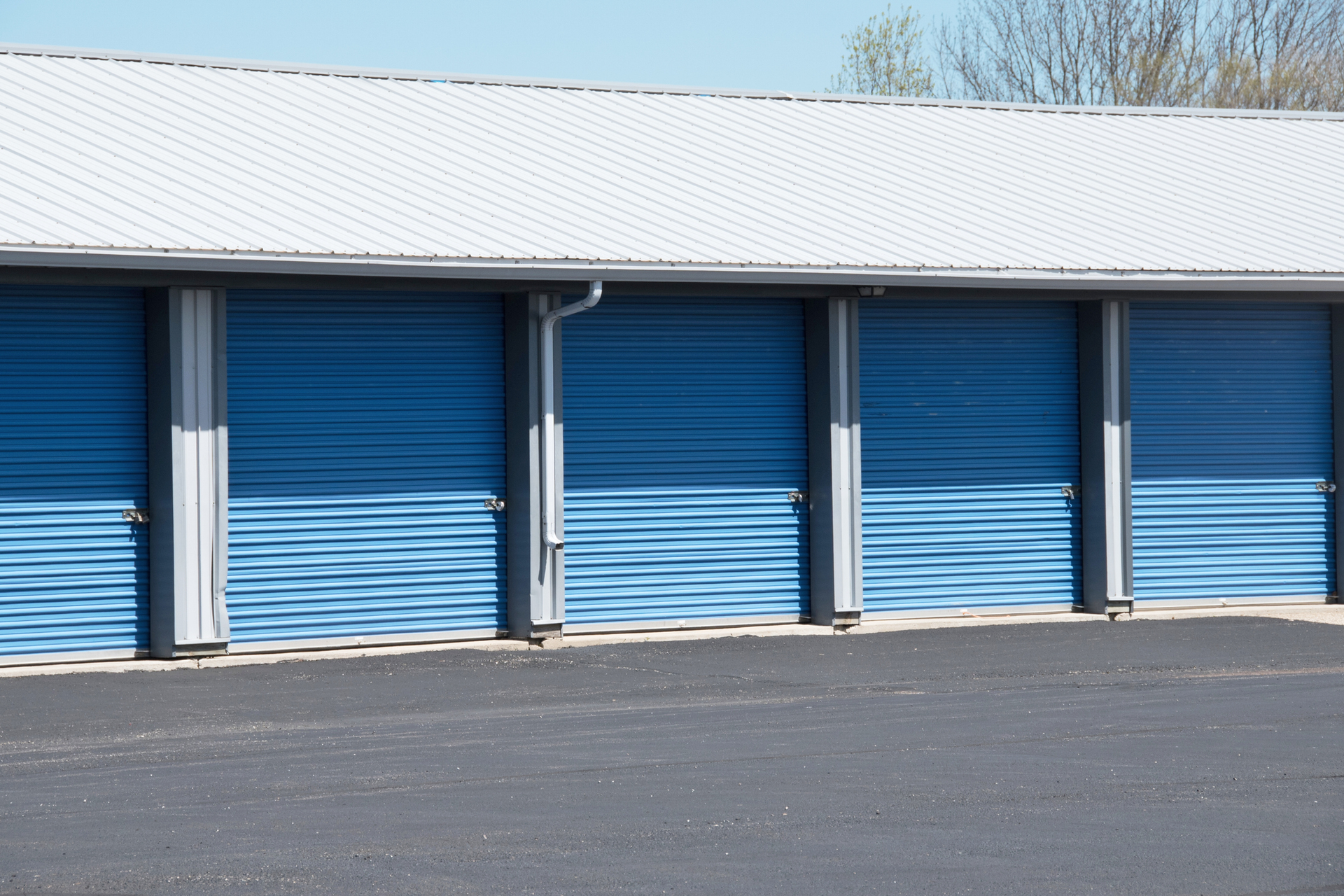 Blue storage unit doors with a corrugated design and metal roof.