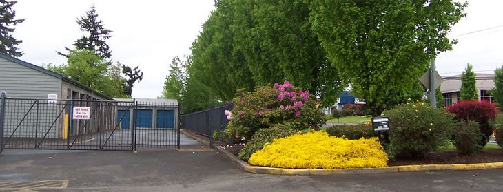 Orange storage unit doors with gray roofs against a backdrop of trees.