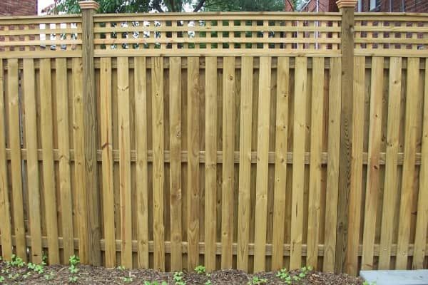 Wooden fence with lattice top, vertical planks, and posts.