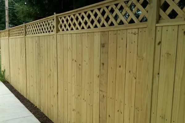 Wooden fence with lattice top along a sidewalk.